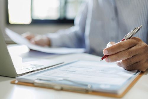 Foto: Person mit Dokumenten und Laptop